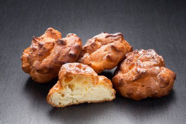 Krem puf Fransız böreği veya profiterol kapatın. Vanilya krem koyu arka plan üzerinde ile klasik eklerleri