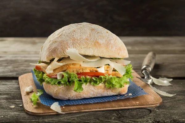 Tavuk göğsü, peynir ve yeşil salata ile ciabatta sandviç ahşap arka planda yakın - Stok İmaj