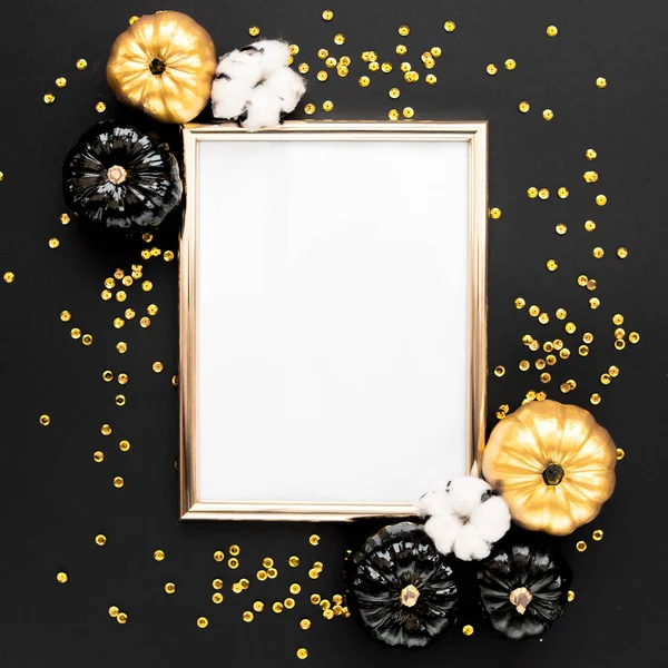 Gold frame decorated with black and gold Halloween pumpkin and tinsel with copy space for text. isolated on black background. Flat lay, top view.