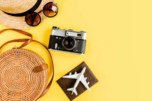 Eco bolsa de ratán, cámara retro, avión modelo, avión y sombrero de paja. Concepto de accesorios del viajero sobre fondo amarillo. — Foto de Stock