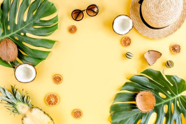 Tropikal çerçeve, arka planda egzotik meyveler ve sarı arka planda tropikal palmiye yaprakları. Düz yatış, üst görünüm