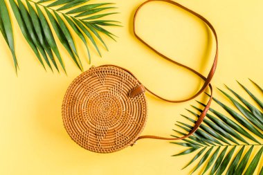 Modaya uygun el yapımı turuncu çanta ve sarı arka planda tropikal yapraklar.. 