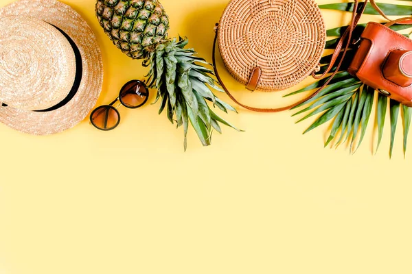 Accesorios mujer viajero: bolsa de bambú, sombrero de paja, hojas de palma tropical monstera, cámara retro sobre fondo amarillo. Piso tendido, vista superior — Foto de Stock