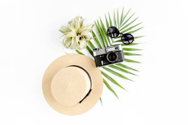 Beyaz arka planda, eski kamera, hasır şapka, güneş gözlüğü ve tropikal palmiye yaprağı olan düz gezgin aksesuarları vardı. Seyahat kavramı arka planı. 