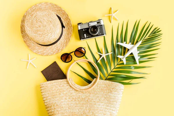 Женские пляжные аксессуары: сумка из ротанга, соломенная шляпа, тропические пальмовые листья, модель самолета, самолет на желтом фоне. Концепция путешествия. Лето — стоковое фото