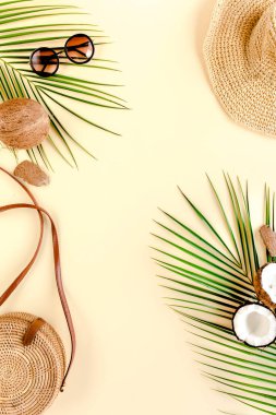 Kadın plaj aksesuarları: bikini, rattan çanta, hasır şapka, sarı arka planda tropik palmiye yaprakları. Yaz arkaplanı. 