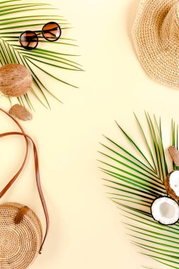 Womans beach accessories: bikini, rattan bag, straw hat, tropical palm leaves on yellow background. Summer background.  clipart