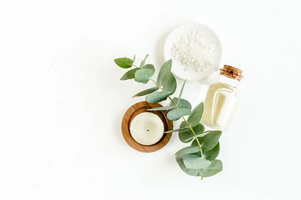 Egy üveg eukaliptusz illóolaj, eukaliptusz levelek fehér alapon. Természetes szerves kozmetikai termékek. Lapos fekvésű, felülnézet. — Stock Fotó