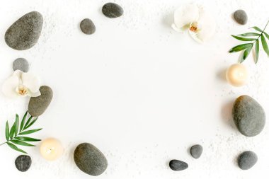 Spa taşları, palmiye yaprakları, çiçek beyazı orkide, mum ve zen beyaz arka plandaki gri taşlar gibi. Düz yatış, üst görünüm