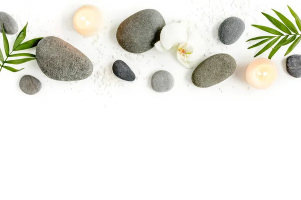 Wellness-Steine, Palmblätter, blumenweiße Orchidee, Kerze und Zen wie graue Steine auf weißem Hintergrund. Flache Lage, Draufsicht — Stockfoto