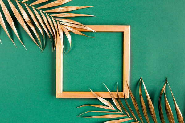 Золотые тропические пальмовые листья и рамка на зеленом фоне. Плоская кладка, вид сверху минимальная концепция.