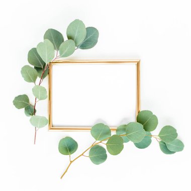 Altın çerçeve yeşil dallar ve beyaz arka planda okaliptüs yapraklarıyla süslenmiştir. Düz uzan, üst görünüm