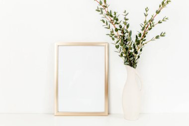 Boş çerçeve modeli ve okaliptüs dalları açık arkaplanda, vazoda. Ev dekoru. Günlük, web sitesi veya sosyal medya kavramı.