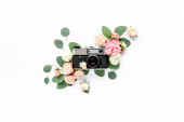 Ročník retro fotoaparát, dekorace růžové a béžové růže květinové pupeny vzor na bílém pozadí. Byt ležel, horní pohled