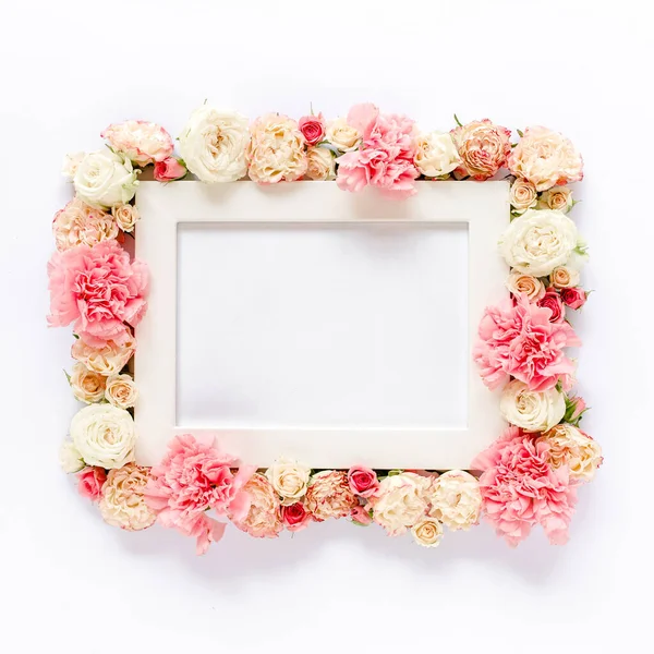 White frame decorated with pink roses flowers and leaves of eucalyptus. Flat lay, top view. Floral background. Floral frame. Frame of flowers.