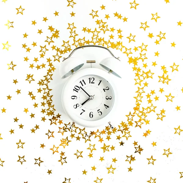 ラウンドフレーム、目覚まし時計は、白、お祝いの背景に黄金の星のコンフェッティ、輝きの装飾をカバーした。クリスマスや新年のパターン。平敷 — ストック写真