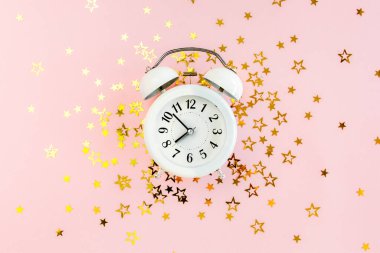 Alarmlı saat, altın yıldızlı konfeti kaplıydı. Pembe, şenlikli bir arka planda süsleme vardı. Noel ya da yeni yıl şablonu. Renkli bir kutlama, doğum günü.