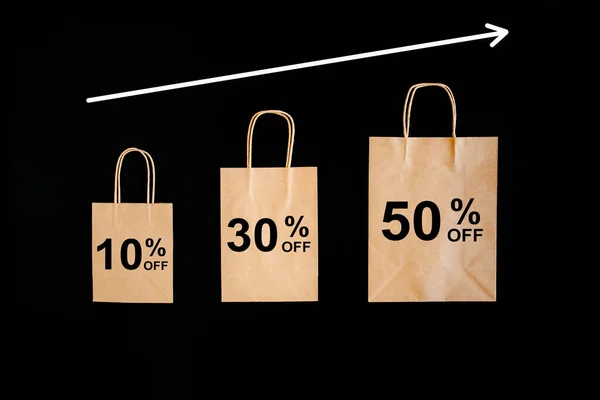 Black Friday sales discount concept. Craft paper bags with word Sale on black background.