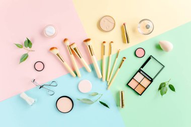 Profesyonel dekoratif kozmetik ve makyaj aletleri renkli arka planda fırçalar. Güzellik ve moda konsepti. Düz kompozisyon. Üst görünüm.