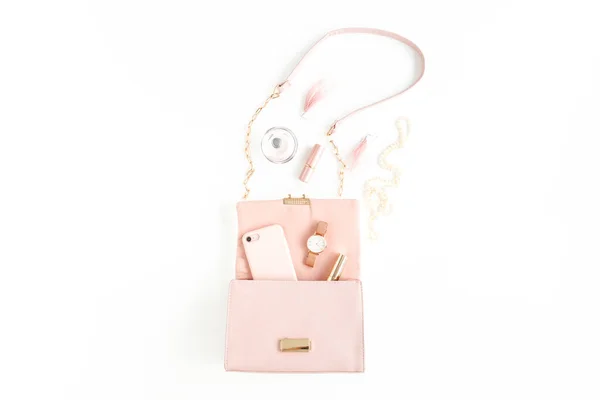 Bolsa rosa das mulheres com acessórios da moda na moda: relógio, perfume, telefone, batom, brincos no fundo branco. Deitado plano, vista superior — Fotografia de Stock