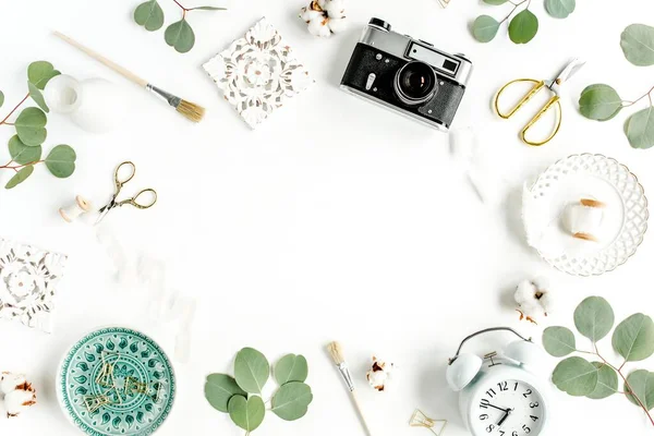 Seramik yaprak canavarlı çalışma alanı, retro kamera, okaliptüs yaprağı, beyaz arka planda aksesuarlar. Düz konum. Üst görünüm