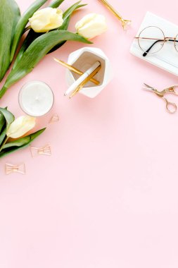 Lale çiçeği buketli, altın aksesuarlı, pembe arka planlı bir kadın çalışma alanı. Düz uzanmış kadınların ofis masası. Üst görünüm kadınsı arkaplan