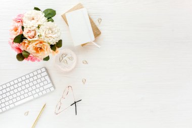 Pembe ve bej güllü kadınların çalışma alanı çiçek buketi, aksesuarlar, günlük, beyaz arka planda gözlük. Düz yerde, üst tarafta. Güzellik günlüğü konsepti.