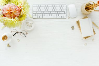 Düz uzanmış kadınların ofis masası. Bilgisayarlı kadın çalışma alanı, pembe ve sarı güller çiçekler, aksesuarlar, günlük, beyaz arka planda gözlük. Üst görünüm