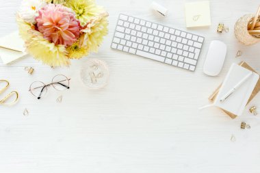Düz uzanmış kadınların ofis masası. Bilgisayarlı kadın çalışma alanı, pembe ve sarı güller çiçekler, aksesuarlar, günlük, beyaz arka planda gözlük. Üst görünüm