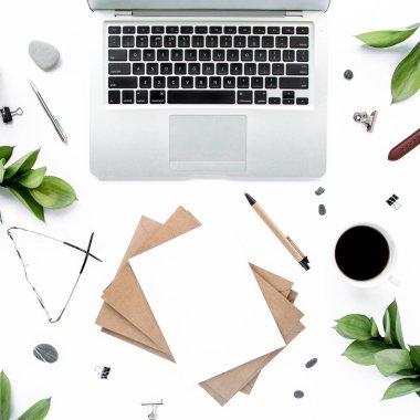 Ofis masası çalışma alanı boş, yeşil yapraklı. Dizüstü bilgisayar, beyaz arka planda gözlük. Dergiler, web siteleri, sosyal medya. Düz yatış, üst görünüm.