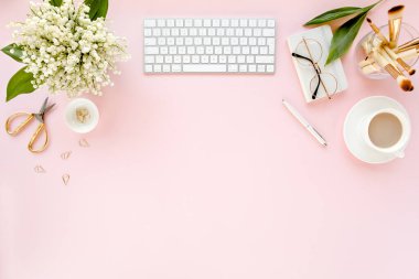 Ofis masasında bilgisayar, leylak ve dosya var. Dergiler. Üst Manzara Düz Yatıyordu. Merkez ofis çalışma alanı. Pembe arka planda kadın moda aksesuarları