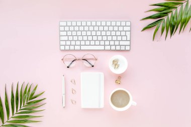 Bilgisayarlı ofis masası, yeşil yapraklı avuç içi, dosya. Üst Manzara. Düz yatıyordu. Merkez ofis çalışma alanı. Pembe arka planda kadın aksesuarları. 