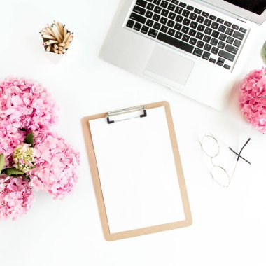 Tarz sahibi kadınlar masası. Çalışma odası, dosya, dizüstü bilgisayar, buket ortanca, beyaz arka planda aksesuarlar. Düz yatıyordu. Üst görünüm.