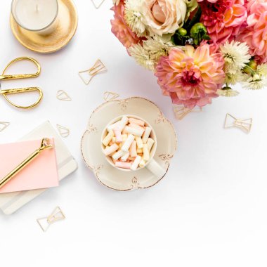 Ev ofisinin masası düzdü. Pembe güllü kadın çalışma alanı, yıldız çiçeği buketi, altın aksesuarlar, beyaz arka planda günlük. Üst görünüm.