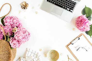 Çalışma odası, dosya, dizüstü bilgisayar, buket ortanca, beyaz arka planda aksesuarlar. Tarz sahibi kadınlar masası. Düz yatıyordu. Üst görünüm.