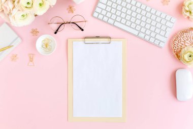 Tarz sahibi, pembe kadınların ofis masası. Bilgisayarlı çalışma alanı, buket ranunculus ve güller, pembe arka planda pano. Düz yatıyordu. Üst görünüm.