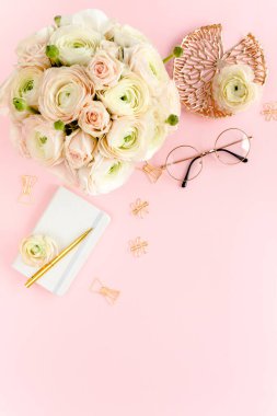 Tarz sahibi, pembe kadınların ofis masası. Çiçek buketi ve güllerle dolu çalışma alanı, pembe arka planda pano. Düz yatıyordu. Üst görünüm.