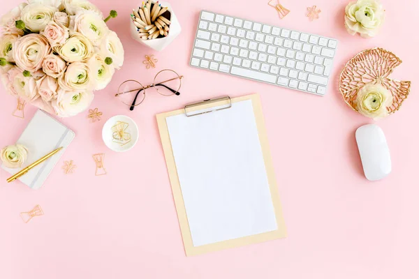 Stilisierter, pinkfarbener Home-Office-Schreibtisch für Frauen. Arbeitsplatz mit Computer, Strauß Hahnenfuß und Rosen, Klemmbrett auf rosa Hintergrund. Flach lag er. Ansicht von oben. — Stockfoto