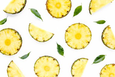 Beyaz arka planda yeşil yapraklı ananas dilimleri. Düz yatış, üst görünüm
