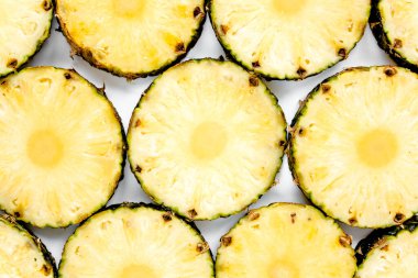 Beyaz arka planda yeşil yapraklı ananas dilimleri. Düz yatış, üst görünüm