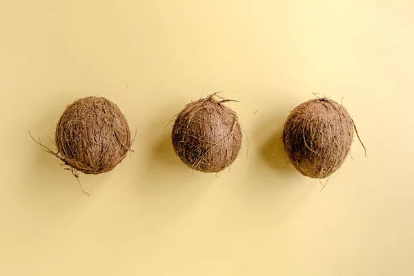 Kokosnötter på gul bakgrund. Lägenheten låg, ovanifrån — Stockfoto