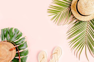Yaz dönemi. Tropik palmiye yaprağı dalları, pembe arka planda hasır şapka ve mesaj için boş alan. Seyahat tatili konsepti. Düz yatış, üst görünüm.
