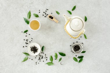 İki beyaz çay fincanı ve yeşil çay yapraklı çaydanlık ile bitki çayı. Düz yerde, üst tarafta. Çay konsepti