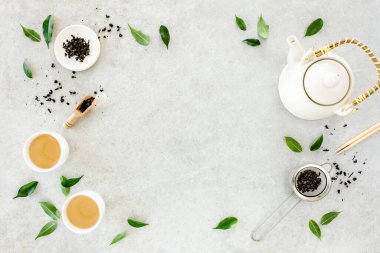 İki beyaz çay fincanı ve yeşil çay yapraklı çaydanlık ile bitki çayı. Düz yerde, üst tarafta. Çay konsepti