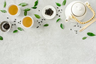 İki beyaz çay fincanı ve yeşil çay yapraklı çaydanlık ile bitki çayı. Düz yerde, üst tarafta. Çay konsepti