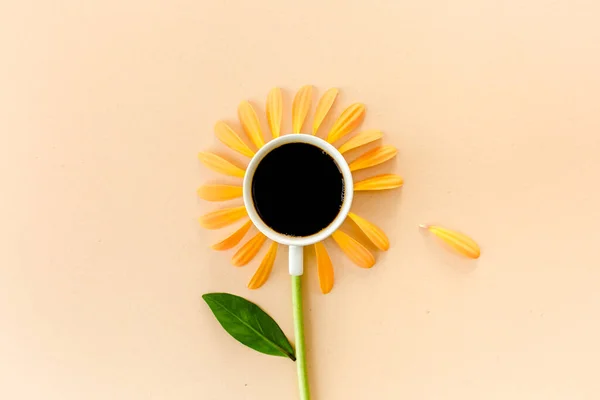 Ένα φλιτζάνι καφέ και πέταλα λουλουδιών σε μπεζ φόντο. Επίπεδο lay, πάνω όψη — Φωτογραφία Αρχείου