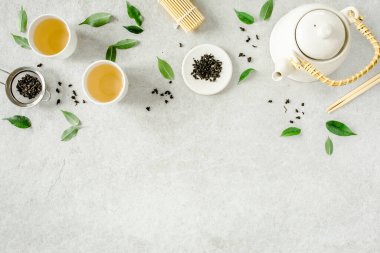 İki beyaz çay fincanı ve yeşil çay yapraklı çaydanlık ile bitki çayı. Düz yerde, üst tarafta. Çay konsepti