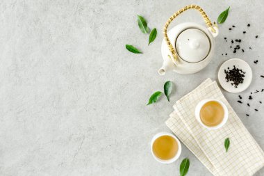 İki beyaz çay fincanı ve yeşil çay yapraklı çaydanlık ile bitki çayı. Düz yerde, üst tarafta. Çay konsepti