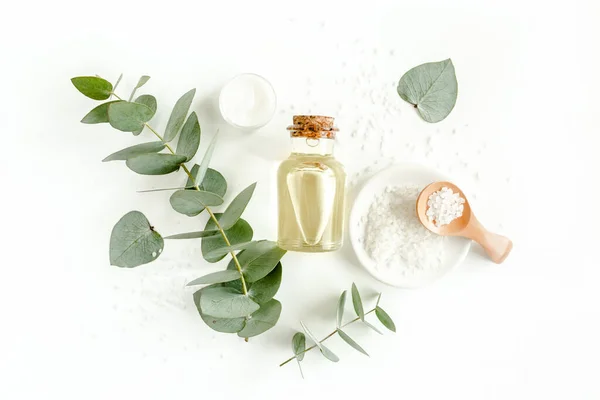 Bottle of eucalyptus essential oil, eucalyptus leaves on white background. Natural Organic cosmetics products. Flat lay, top view. — Stock Photo, Image