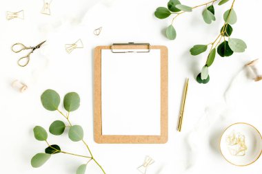 Beyaz arka planda pano ve yaprak okaliptüslü çalışma alanı. Ev ofis masasının düz yatağı, üst görünüm. 